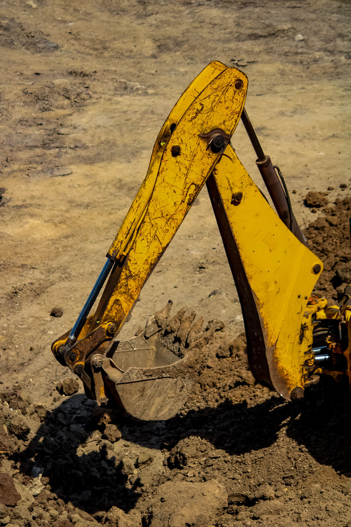 Yellow excavator shovel in a dirt field